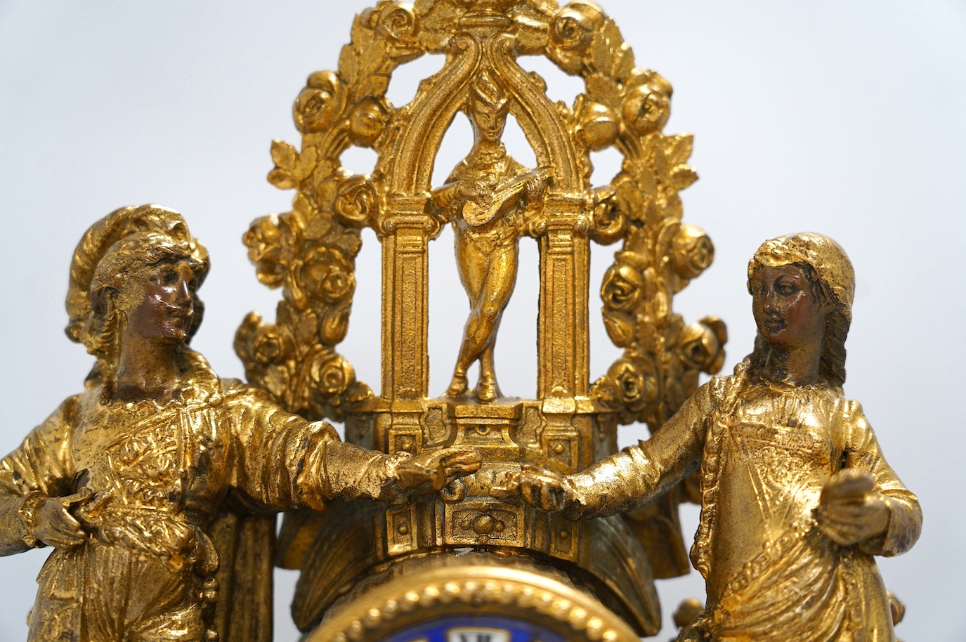 A large gilt metal figural mantel clock with floral porcelain dial and panels, under a glass dome, 52cm high (including stand). Condition - fair, not tested as working
